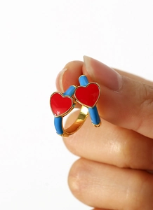 Detailed macro view of heart-shaped gold earrings with red and blue enamel finish