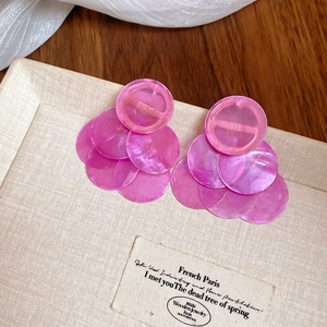 Detail of pink shell earrings with layered circular pendants on a jewelry box lid