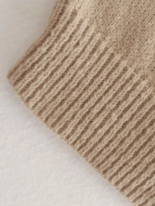 Macro detail of the camel ribbed knit cuff showing soft texture and fine stitching
