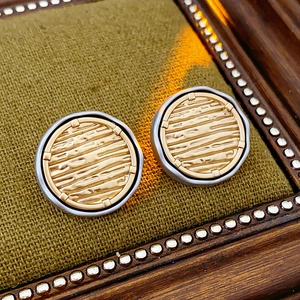 Detail of vintage round gold earrings with horizontal texture in a wooden frame