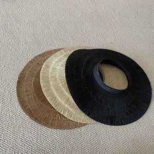 Top-down view of woven straw sun hats in black, beige and brown with frayed tassel edges