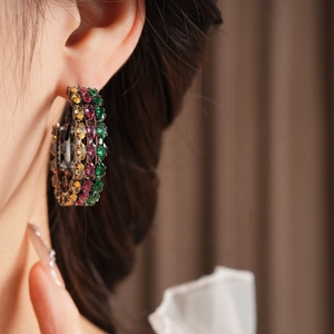 Close-up of vintage hoop earrings with three rows of colorful zircon stones on model