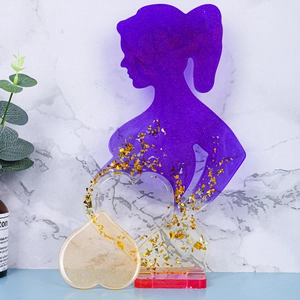 Dettaglio di silhouette femminile in resina viola e ciondoli a cuore dorati per artigianato
