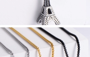 Macro detail of Eiffel Tower pendants in silver, gold, and black titanium steel finishes