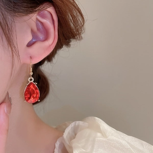 Detail of elegant red teardrop gemstone earrings with gold hooks on a model