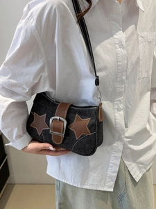 Detail of black denim shoulder bag with brown star patches and metal buckles
