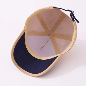 Internal detail of a two-tone baseball cap featuring reinforced stitching and metal fastener