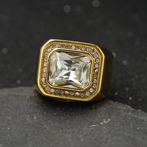 Gros plan d'une bague en acier doré avec zircon rectangulaire sur un socle en pierre
