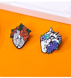 Macro detail of anatomical heart enamel brooches with floral decor on orange background