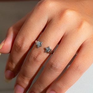 Close-up of a silver stainless steel adjustable ring featuring a double star design
