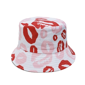 Détail rapproché des motifs lèvres rouges et roses sur le tissu blanc du chapeau