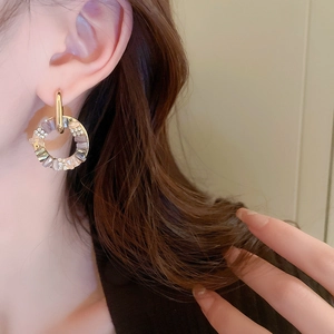 Close-up of a gold geometric earring with sparkling crystals on a female model