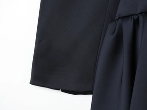 Détail macro de la texture du tissu noir et du drapé fluide de la mini robe