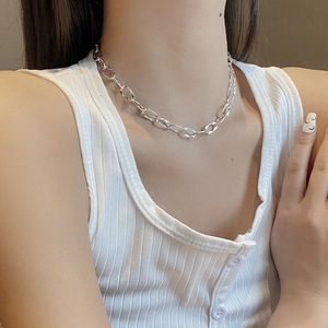 Detailed view of silver thick geometric chain necklace worn by a female model