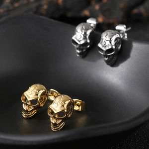 Macro shot of punk style stainless steel skull earrings in gold and silver finish