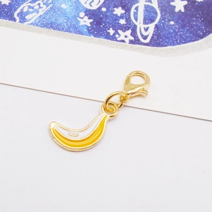 Detailed close-up of a banana shaped enamel charm with golden lobster clasp and yellow finish