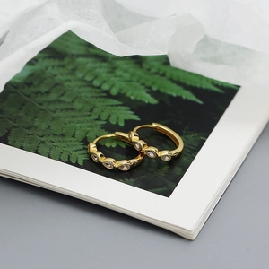 Close-up of golden teardrop earrings with zircons on a decorative botanical book