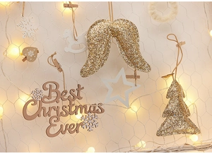 Christmas wall ornaments with golden glitter wings and wooden signs on white grid