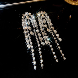 Macro shot of sparkling silver tassel earrings with multiple rhinestone chains on black background