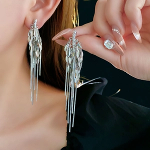 Macro detail of silver tassel earrings with wheat leaf design and long metallic chains