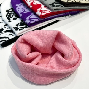 Detail of pink knitted beanie with skull jacquard pattern and stack of color variants