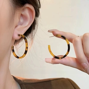 Close-up of tortoise shell pattern C-shaped earrings with vintage resin texture