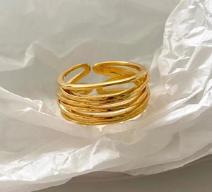 Macro shot of minimalist gold multilayer coil open ring on a textured white background
