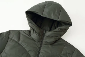 Detail of hooded olive green puffer coat with quilted texture and matching zipper