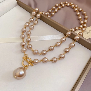 Détail d'un collier de perles champagne avec fermoir à bascule doré et pendentif perle