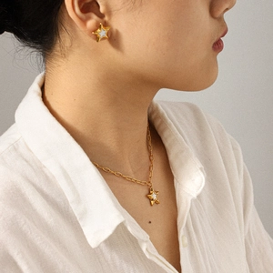 Close-up of a model wearing golden star-shaped jewelry set with white enamel inlay