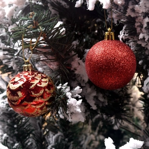 Detail of red Christmas balls with gold textures and glitter on snowy tree branches