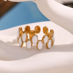 Macro detail of 18K gold plated ring with white enamel oval inlays on stone display