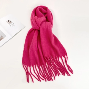 Detail of soft mohair knit scarf in hot pink featuring fringe ends and fluffy texture