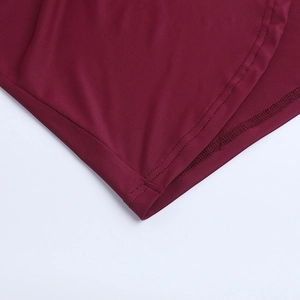 Close-up of fine stitching and smooth knit fabric on wine red lace dress hem
