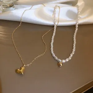 Detail of layered gold heart necklace and pearl beaded chain on white silk background
