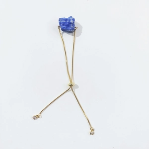Detail of adjustable gold bracelet featuring irregular raw blue crystal and slider clasp