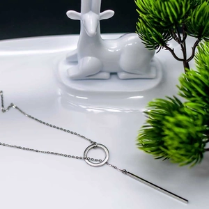 Silver stainless steel geometric necklace with circular and bar pendants on white surface