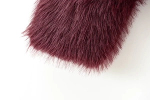 Macro shot of dense burgundy faux fur texture on a cropped women's fashion jacket