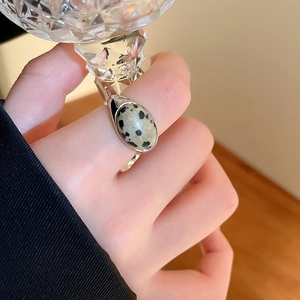 Detail eines Dalmatiner-Jaspis-Rings an der Hand eines Models, das ein Kristallglas hält