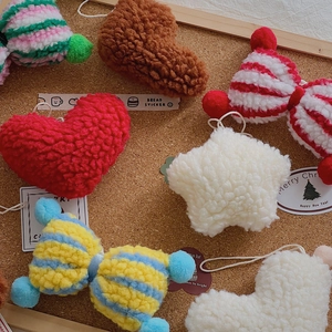 Various handmade lamb wool plush Christmas ornaments in heart and star shapes on cork board