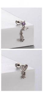 Detail of titanium steel ear studs featuring butterfly and heart shapes with purple zircons