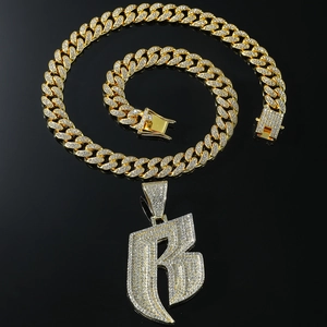 Macro shot of gold-plated iced-out letter B pendant with sparkling Cuban chain links