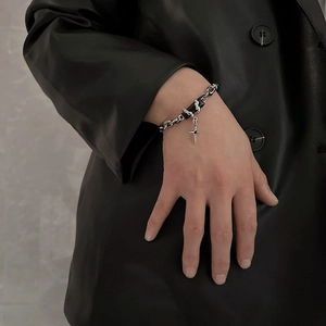 Detail of silver titanium steel bracelet with black beads and cross pendant on wrist