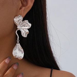 Detail shot of large silver floral earrings with hammered metal texture on a model