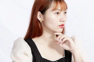 Close-up of a gold Hamsa hand earring with cut-out design worn by a model