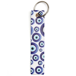 Detailed view of white faux leather keychain with blue evil eye pattern and silver ring
