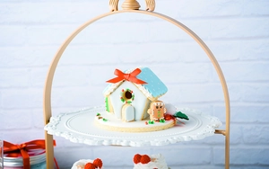 Close-up of a 3D gingerbread house and gingerbread man on a white cake stand