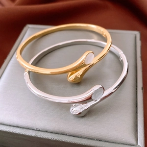 Detail of gold and silver crossover bangles with white oval shell inlay on silk