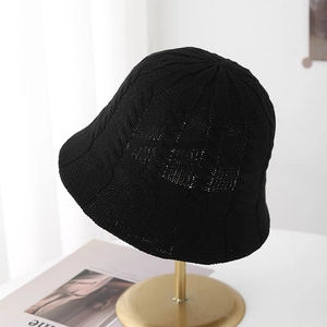 Minimalist black hollow knit bucket hat with cable stitch pattern on display stand