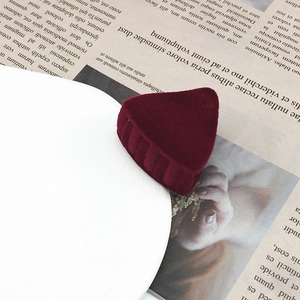 Detailed view of a burgundy velvet triangle hair clip on a minimalist white tray